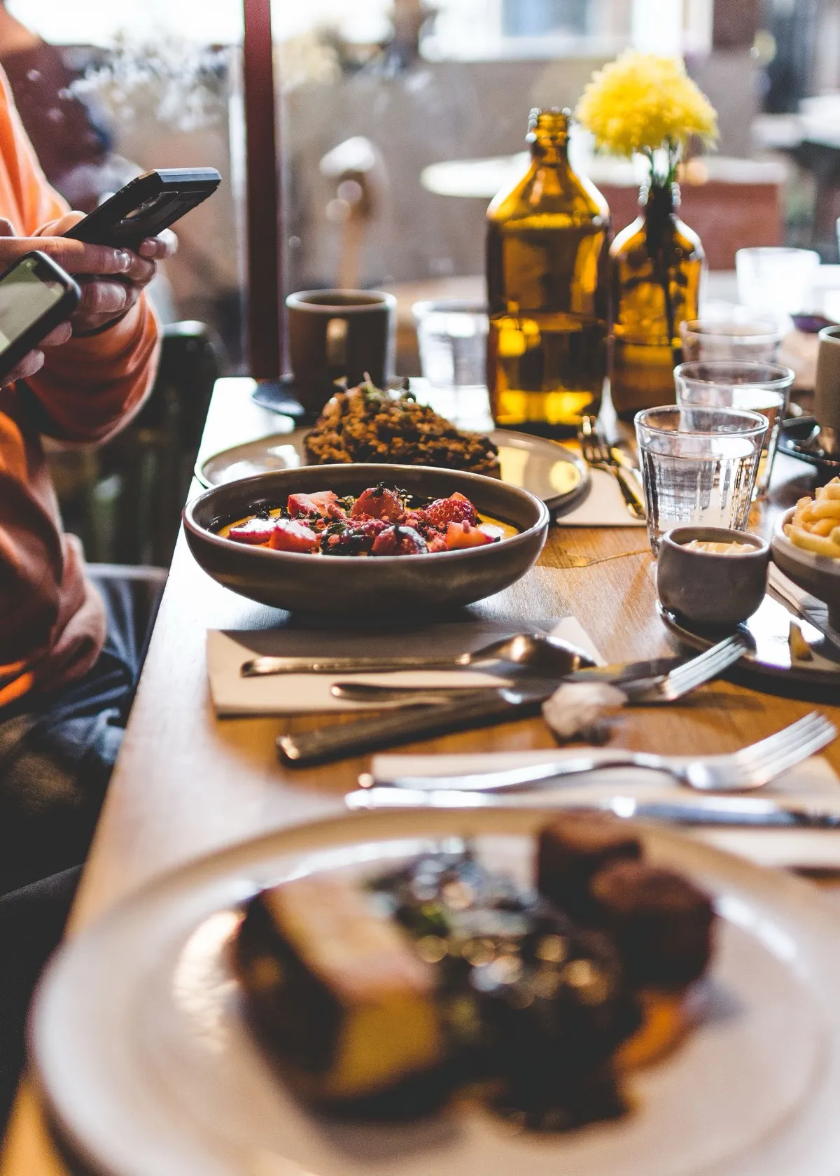 Amigos en la mesa de un bar con sus móviles y platos para compartir